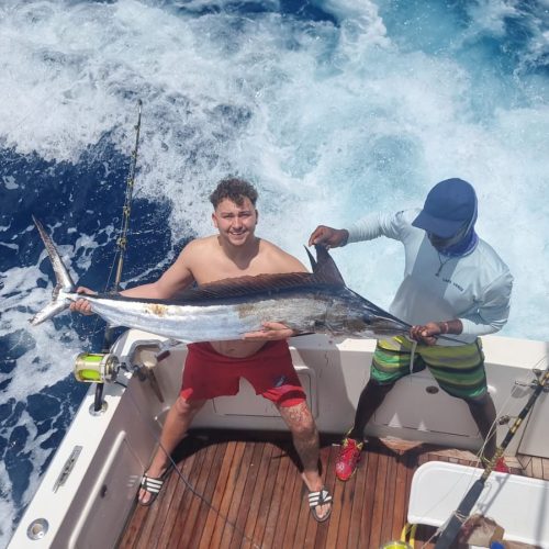 A man holding a sword fish on the deck of a boat out at sea in Cape Verde